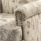 Fauteuil rembourré en bois avec motif floral, accoudoirs à panneaux et dossier en forme de bosse de chameau.